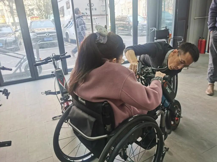 于文涛向一位残障女孩讲解轮椅车头安装步骤