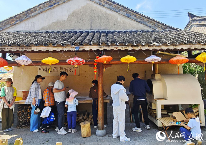 游客在窑烤面包前排队等待制作现烤面包。人民网记者 周坤摄