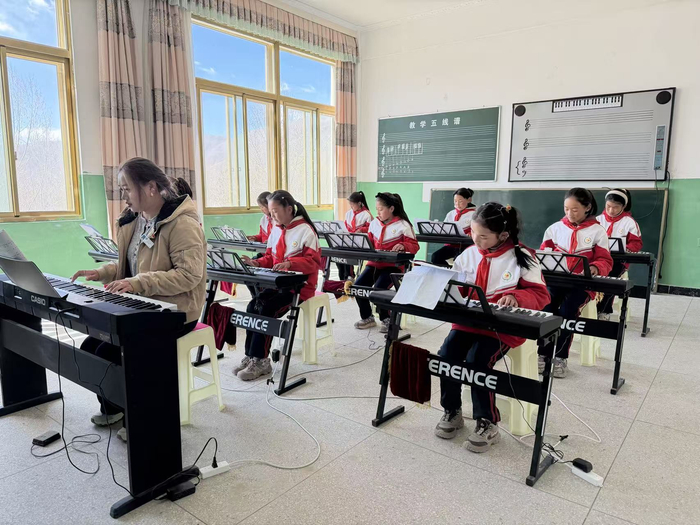 图为南木林县卡孜乡完小钢琴社团老师带领学生练琴。