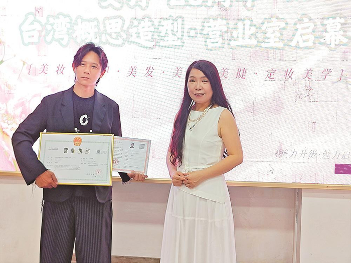     22日，韩再村（左）领取了大陆美发师职业技能等级证书与营业执照。本报记者 吴洪 摄