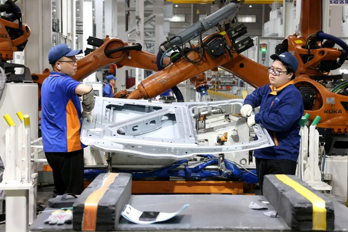 4月16日，在福州荻原泰山友模具冲压有限公司生产车间内，工人配合机器人在生产汽车车身钣金件产品。王旺旺摄