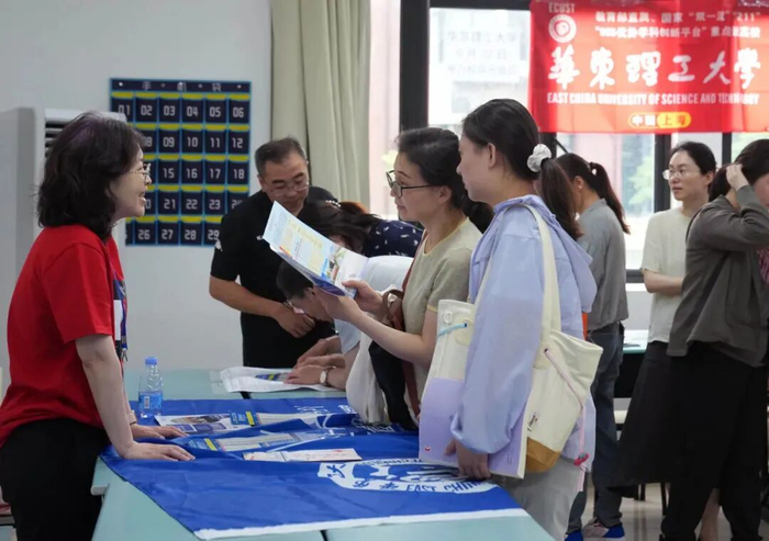 2025年6月15日，华东理工大学的招生老师（左）与考生及家长交流/新华社记者刘颖 摄
