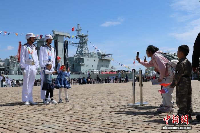 4月22日，北部战区海军舰艇开放活动首日，家长在码头为小朋友拍照。张孝鹏 摄