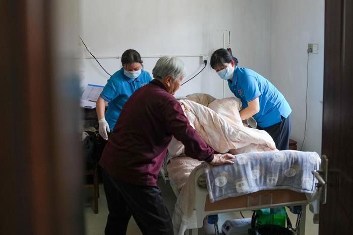 长期照护师和搭档为失能老人更换床单。新华社记者李博 摄