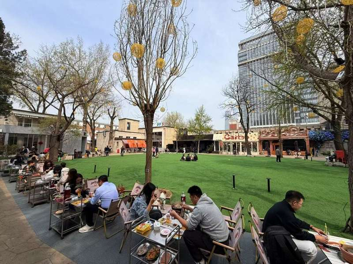 4月2日中午，食客在北京友谊商店室外草坪露天就餐。新华社记者 张骁 摄