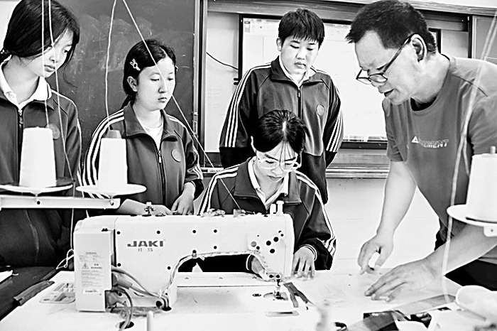 湖南省江永县职业中专教师指导学生进行服装裁缝实践操作。田如瑞摄/光明图片