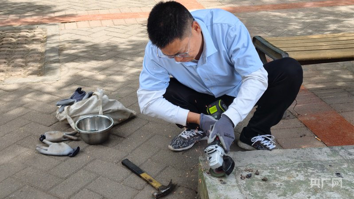 郑州市民卢柯柯在用角磨机清除路面的废弃地钉（央广网记者  郝振青）