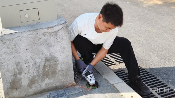 郑州市民万付刚在用角磨机清除路面的废弃地钉（央广网记者  郝振青）