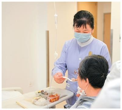 近日，在上海市肺科医院免陪照护病房，医疗护理员给患者喂饭。新华社记者 刘颖摄