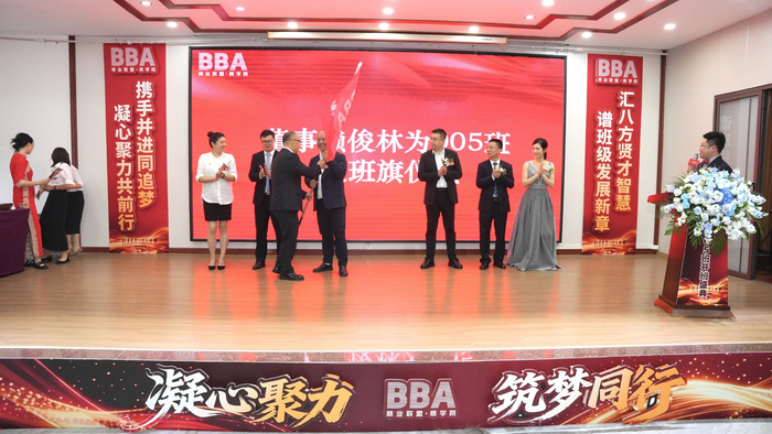 【图:赣州BBA商学院董事赖俊林向005班执行班长王永荣授旗】