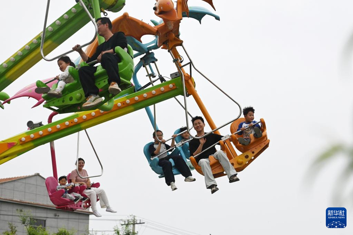 5月1日，在河南省沁阳市怀府恐龙园，游客体验“滑翔飞翼”游乐项目。新华社发（杨帆摄）