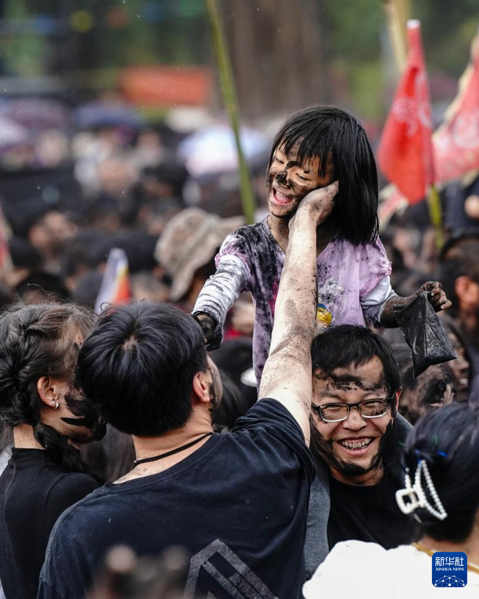 5月1日，家长带着小朋友在云南墨江参加“抹黑脸”民俗活动。新华社记者 陈欣波 摄