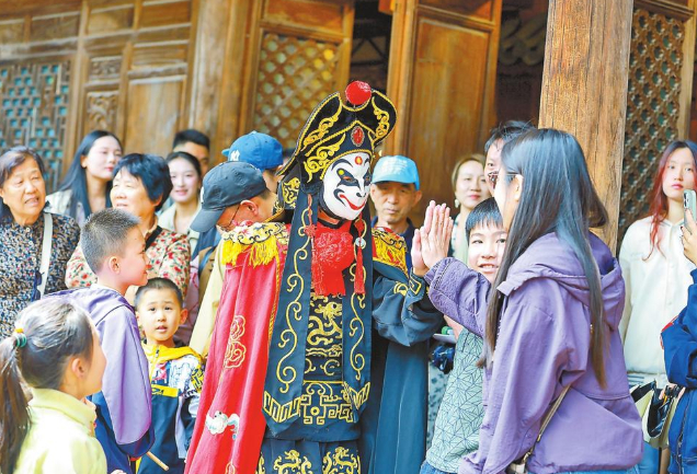 游客在和顺古镇与川剧变脸演员互动。云南日报-云新闻记者 胡妤雅 摄