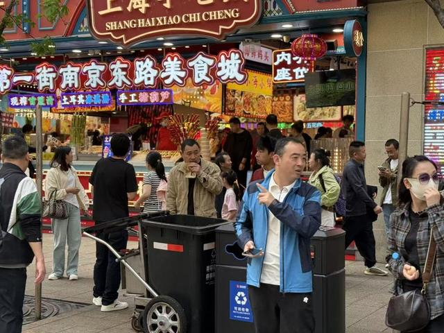 游客在南京路步行街美食城门口旁的垃圾桶旁随吃随扔。沈思怡 摄