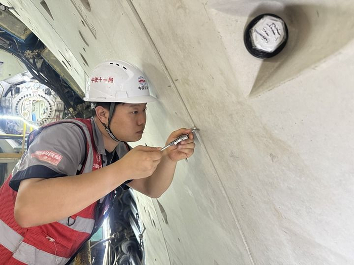 2025年9月30日，在甬舟铁路金塘海底隧道，孙文博测量管片拼装间隙。新华社发（陈星 摄）