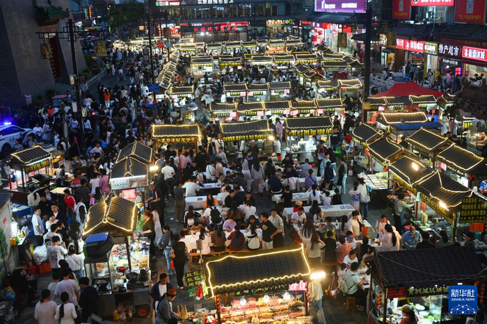5月1日晚，在河南省开封市鼓楼夜市，游客品尝各种小吃。新华社发（李俊生摄）