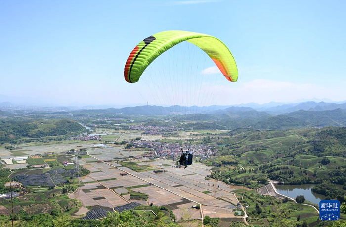 5月1日，游客在浙江省金华市武义县大斗山飞行营地乘坐滑翔伞。新华社发（张建成摄）