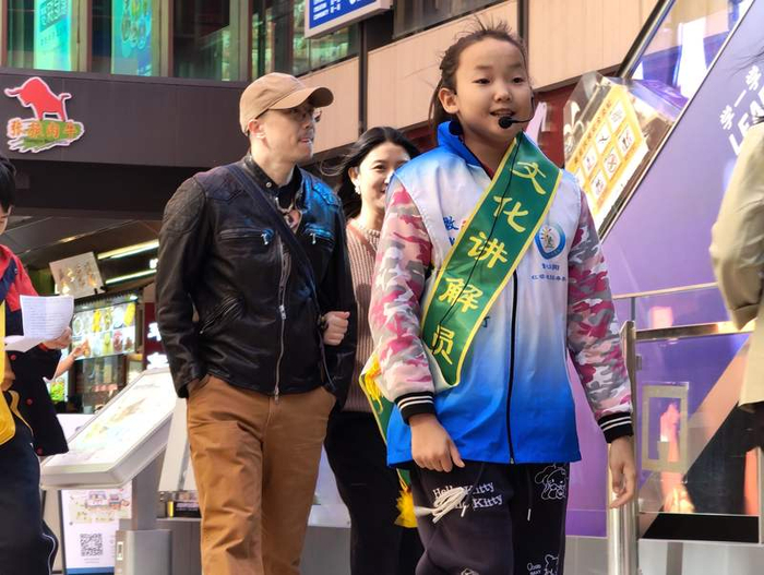 景山街道组织辖区内的学生志愿者为游客讲解隆福寺的历史故事。