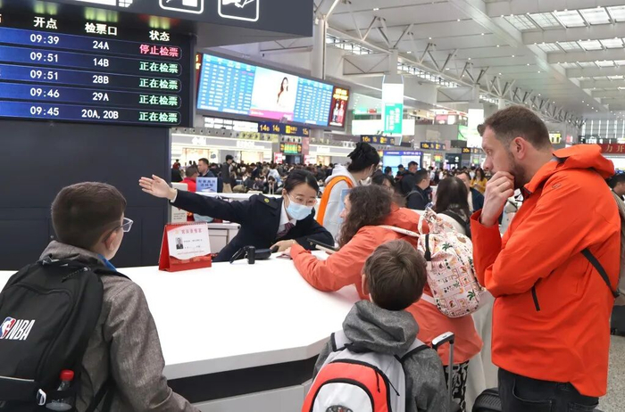 上海虹桥站工作人员为外籍旅客提供咨询服务。   过云松  摄