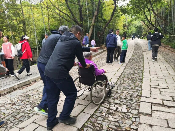工作人员帮高龄老人推轮椅