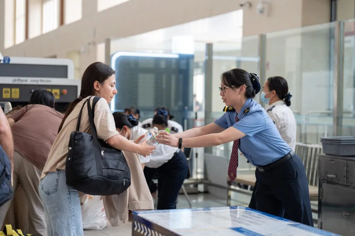 东兴市站副站长甘甜为外籍旅客递行李。通讯员 凌靖智 摄