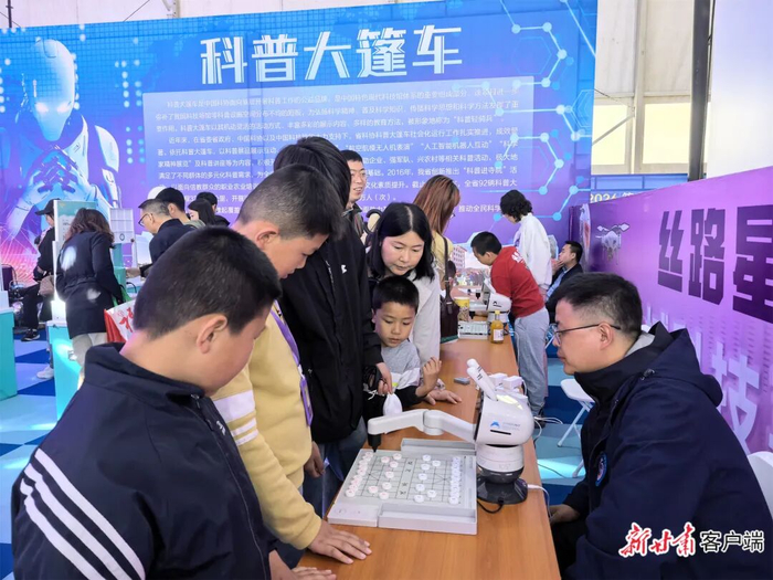 孩子们在金城科技嘉年华活动上与下棋机器人对弈。