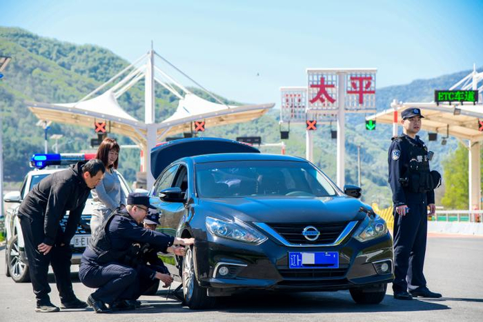  图为民警在高速路口帮助外地游客维修故障车辆。