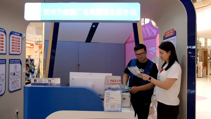 图为求职者在贺州市麒麟广场商圈就业服务站与工作人员沟通