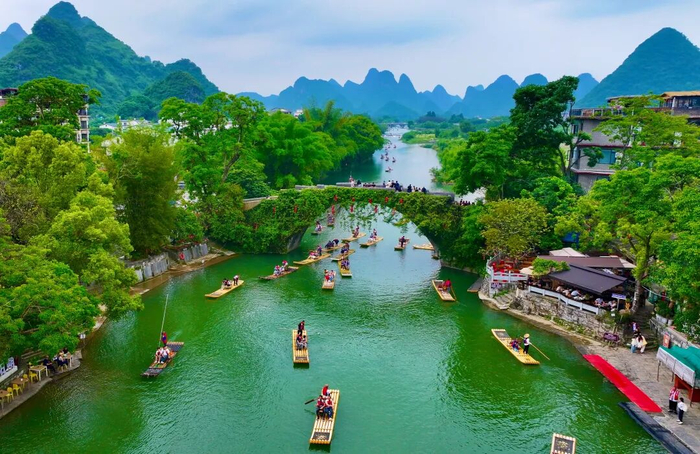 5月2日，在阳朔县白沙镇遇龙河，游客搭乘竹筏在如画的山水间畅游，乐享快乐假期。 记者李凯 摄