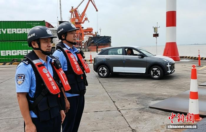 新沙港码头，黄埔边检站移民管理警察对装载出口国产新能源汽车的船舶进行监护。刘腾 摄