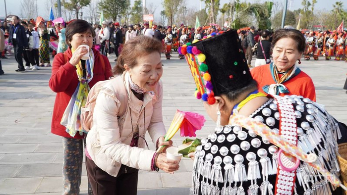 目瑙纵歌活动现场，游客品尝景颇族美酒（央广网记者  魏文青  摄）