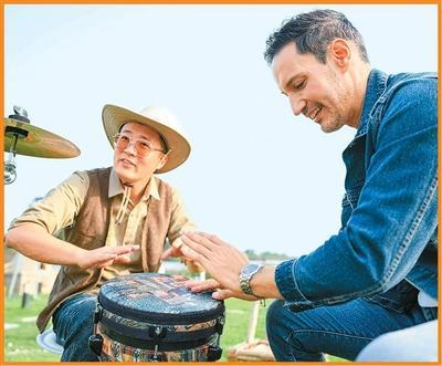 金文凯（左）正在与外国自媒体博主交流非洲鼓打击技巧。俞中岳摄