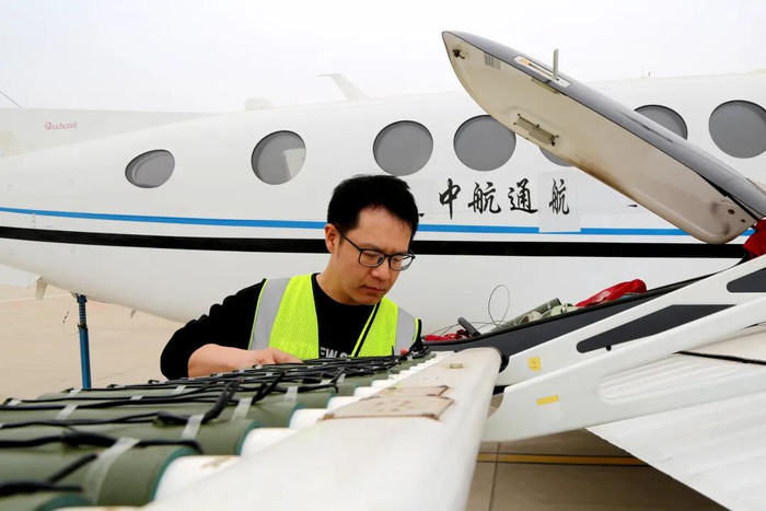 天津市人工影响天气办公室的工作人员正在为飞机装配焰条。摄影：郭玲
