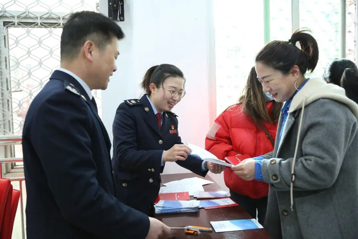 高翠霞（左二）向建筑企业管理人员发放税收优惠政策宣传资料，现场解答企业的涉税问题。庄婧 摄