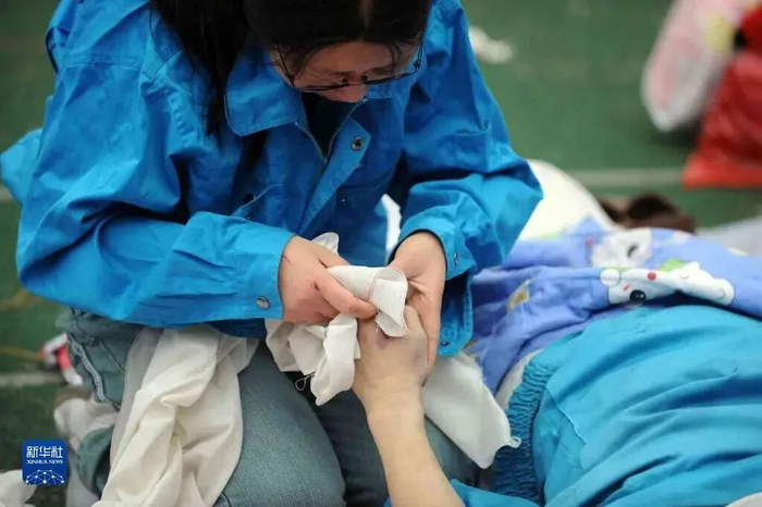 张关容在擦拭丈夫谭千秋的遗体。图片来源：新华社