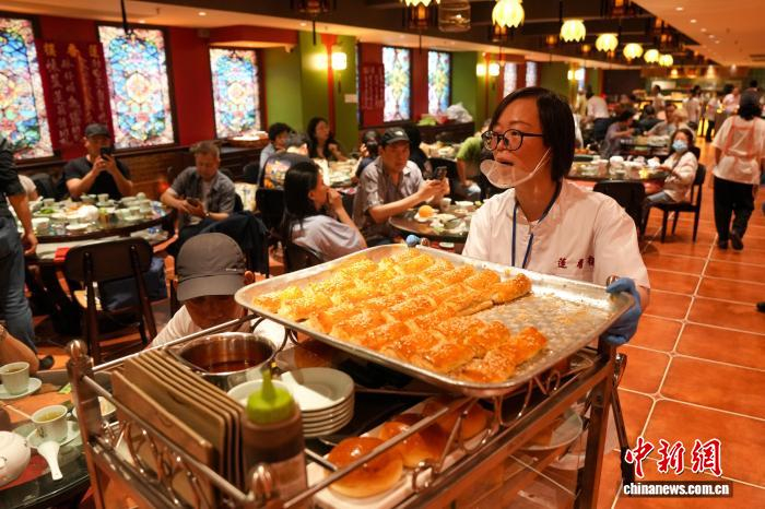 5月11日，莲香楼上环新店正式开业，店员推着手推车向食客售卖点心。　中新社记者 张祥毅 摄