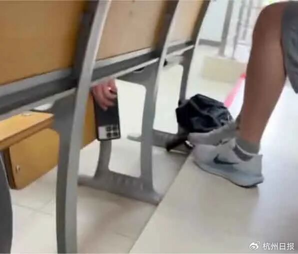 现场视频显示男生将手机伸到桌子下方偷拍 图源：“钱江晚报”微信公众号​