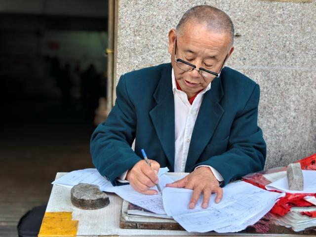 姜明典在小摊前写信。受访者供图