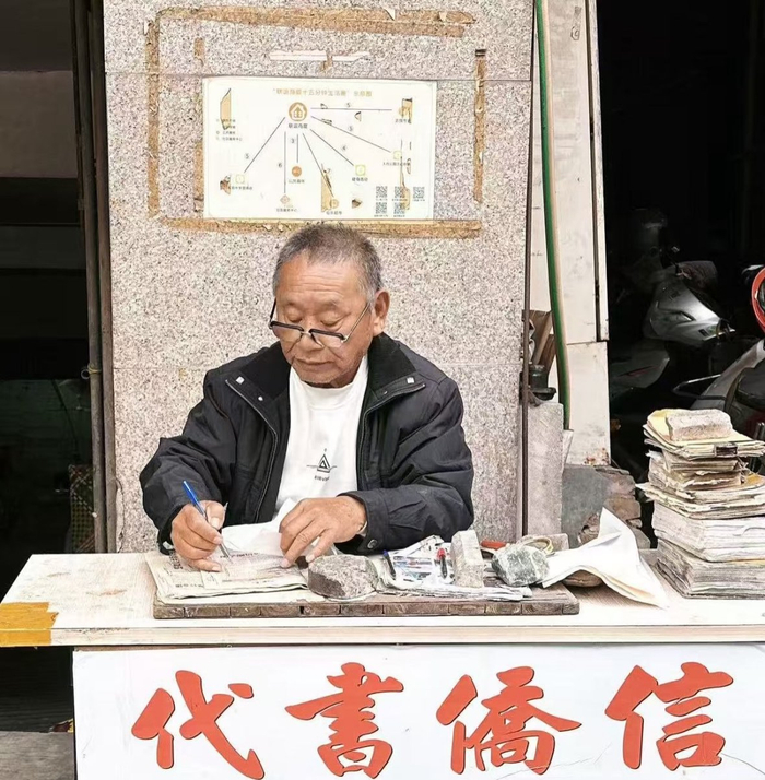 姜明典在小摊前写信。受访者供图