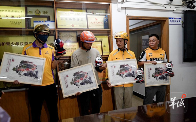 民警为外卖骑手送上越秀公安拼图以及公安醒狮。图/羊城晚报记者 蔡嘉鸿 摄 