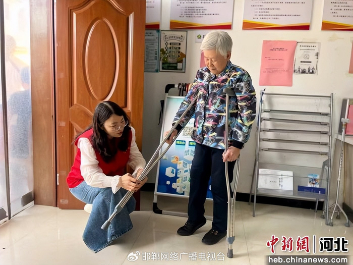 图为工作人员为残疾人免费发放拐杖并调试适配。 王晓芳 摄