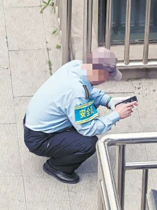 北京西站南广场公交站4站台，一名工作人员在吸烟。