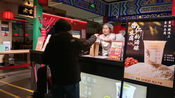 大兴机场航站楼商业店面，工作人员正在细致地为旅客提供服务