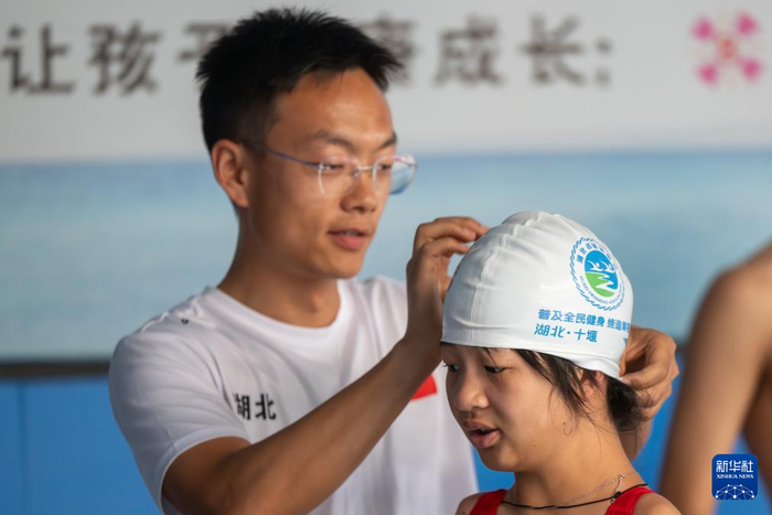 　　5月12日，在湖北随州一家游泳馆，教练李旭阳（左）帮刘三华戴泳帽。新华社记者 杜子璇 摄