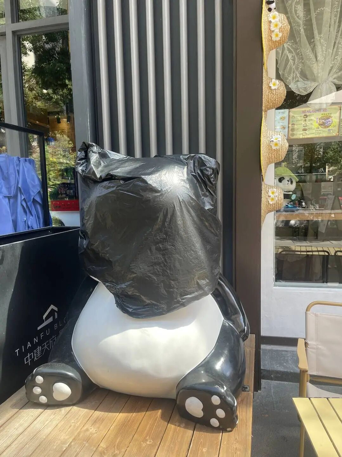 在杨女士的店门前，涉案大熊猫雕塑被套上黑色塑料袋