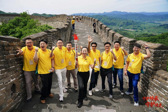 图为火炬传递手以及众人攀登长城活动