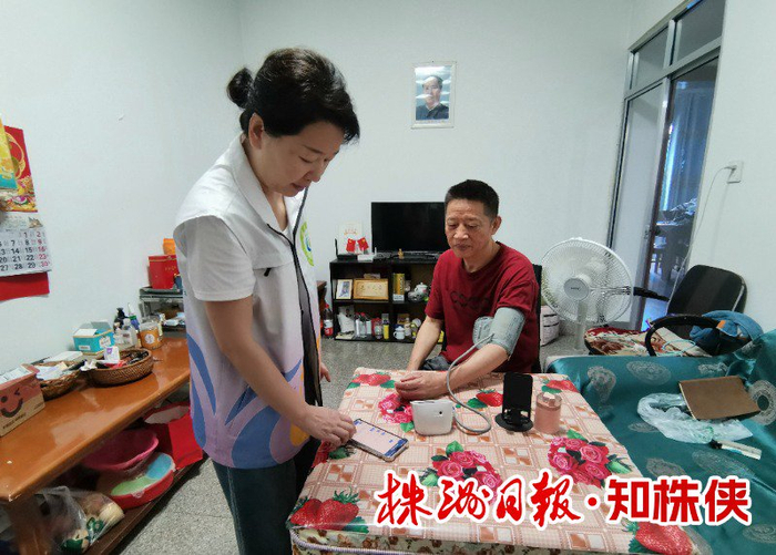 王湘鄂为文先生做检查，在手机上看血压、心率数据。记者/董介 摄
