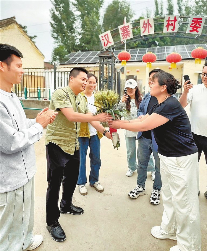 汉寨外村村民为陈鹏（左二）送上一束“麦穗花”，表达欢迎与感谢。 刘冬 摄