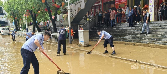 图为都匀市公安局民辅警清扫道路淤泥