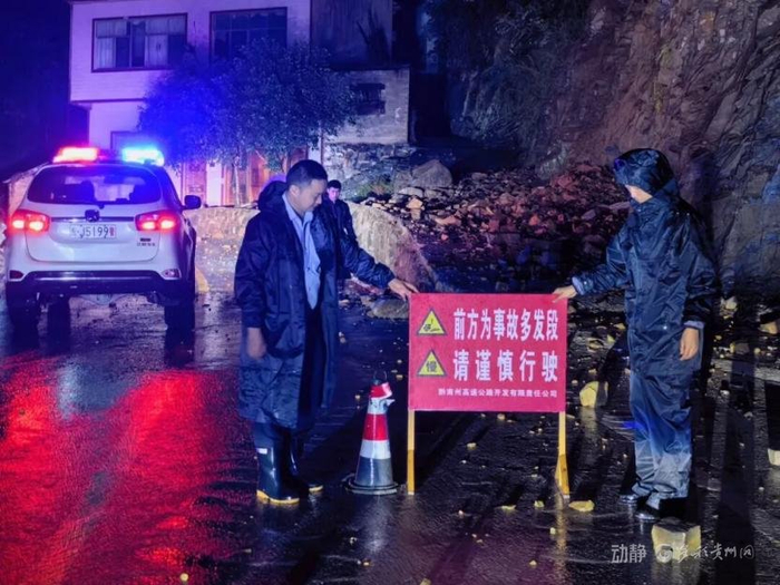 图为罗甸县公安局民警在山体滑坡路段设置警示标志